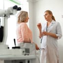 female ophthalmologist gesturing while in talking with her female patient