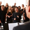 Choir members dressed in black clothes singing before a conductor