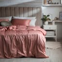 Bed with beautiful silky linens in stylish room interior