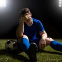 A disappointed soccer player sitting on grass