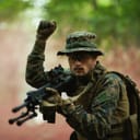 Soldier in full gear signaling "stop" with a closed-fist