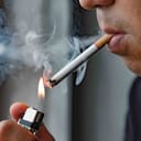 A close up of a young man lighting a cigarette