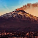 Catania skyline with Mount Etna in the background emitting smoke during dawn, Sicily Island, Italy