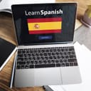 Laptop on desk with "Learn Spanish" prompt displayed on the screen with Spanish flag and 'enter' option