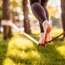 close-up of a girl walking on a slackline in a park at sunset