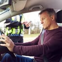 male driver stopped for a traffic violation by a police officer who's using a digital tablet to write a speeding ticket