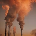 Tall industrial smokestacks emitting smoke and gases.