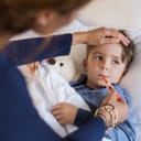 Woman taking a small boy's temperature orally