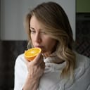 Woman trying to smell half an orange