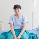 Young man in hospital gown sitting smiling