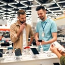 Sales consultant advises man who chooses new smartphone in store of household appliances, electronics and gadgets. Professional consultation in store. Sale Day.