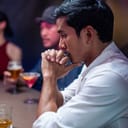 A sad man sitting at a bar with a glass of whiskey in front of him