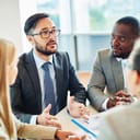 serious Asian businessman speaking at a meeting with colleagues listening attentively
