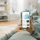 A person lying on a couch browsing the internet on their smartphone