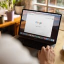 Person looking at the Google starting page displayed on laptop monitor