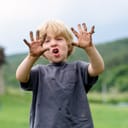 A child showing his muddy hands.