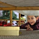 excited boy in pajamas reaching for a wrapped gift under the bed