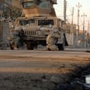 U.S. Army Soldiers attached to Heavy Company, 3rd Squadron, 3rd Armored Cavalry Regiment take cover behind their vehicle after hearing small arms fire in the distance in Mosul, Iraq, Jan. 17, 2008.