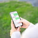 A person writing a text message on a phone while walking outdoors