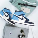 blue and white nike air jordan 1 shoes with outfit of the day on white background