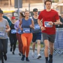 a group of city marathon runners with crowd cheering them on toward the finish line