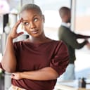 irritated businesswoman rolling her eyes in reaction to what's happening behind her back in the office