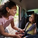 Woman puts on a child's seat belt in the back of a car