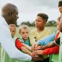 a junior football team stacking their hands with their coach