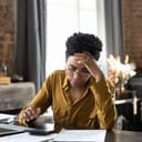 A young female business owner visibly upset and stressed while handling financial documents.