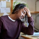 Man with closed eyes resting his head on the arm and table