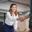 a smiling woman shaking hands with a potential employer during a job interview