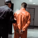 Prisoner in handcuffs being escorted by a correction officer