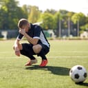 sad soccer player with ball on the field after losing the game