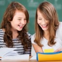 Two classmates laughing while seated at a table