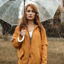 Disappointed woman standing under an umbrella in rain