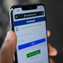 person holding an iPhone 6 displaying Facebook on a mobile browser