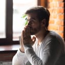A young man sitting down at a table deep in thought