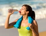 Girl on the beach taking a sip of water