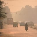 The streets are filled with vehicles and people moving amidst heavy smog, highlighting the challenges posed by air pollution in urban areas.