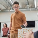 teenage boy placing a smartphone into a no-gadget box in a classroom