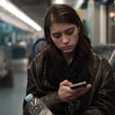 Girl with sad expression on her face using a smartphone while riding public transportation