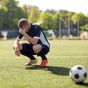 An upset soccer playing squatting in the filed
