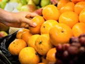 Person picking out oranges from a large basket