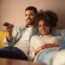 close-up of a young couple comfortably seated in their living room as they watch TV together