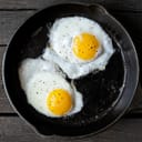 Couple of fried sunny-side-up eggs in pan