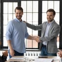 A proud boss shaking employee's hand at a meeting