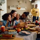 Happy multiracial parents and their kids laughing during family meal on Thanksgiving in dining room.