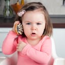 A female toddler playing with a hairbrush as if it was a telephone