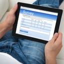 Person looking at a survey on his tablet while resting on the couch