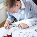 Man inspecting architecture blueprints under a magnifying glass